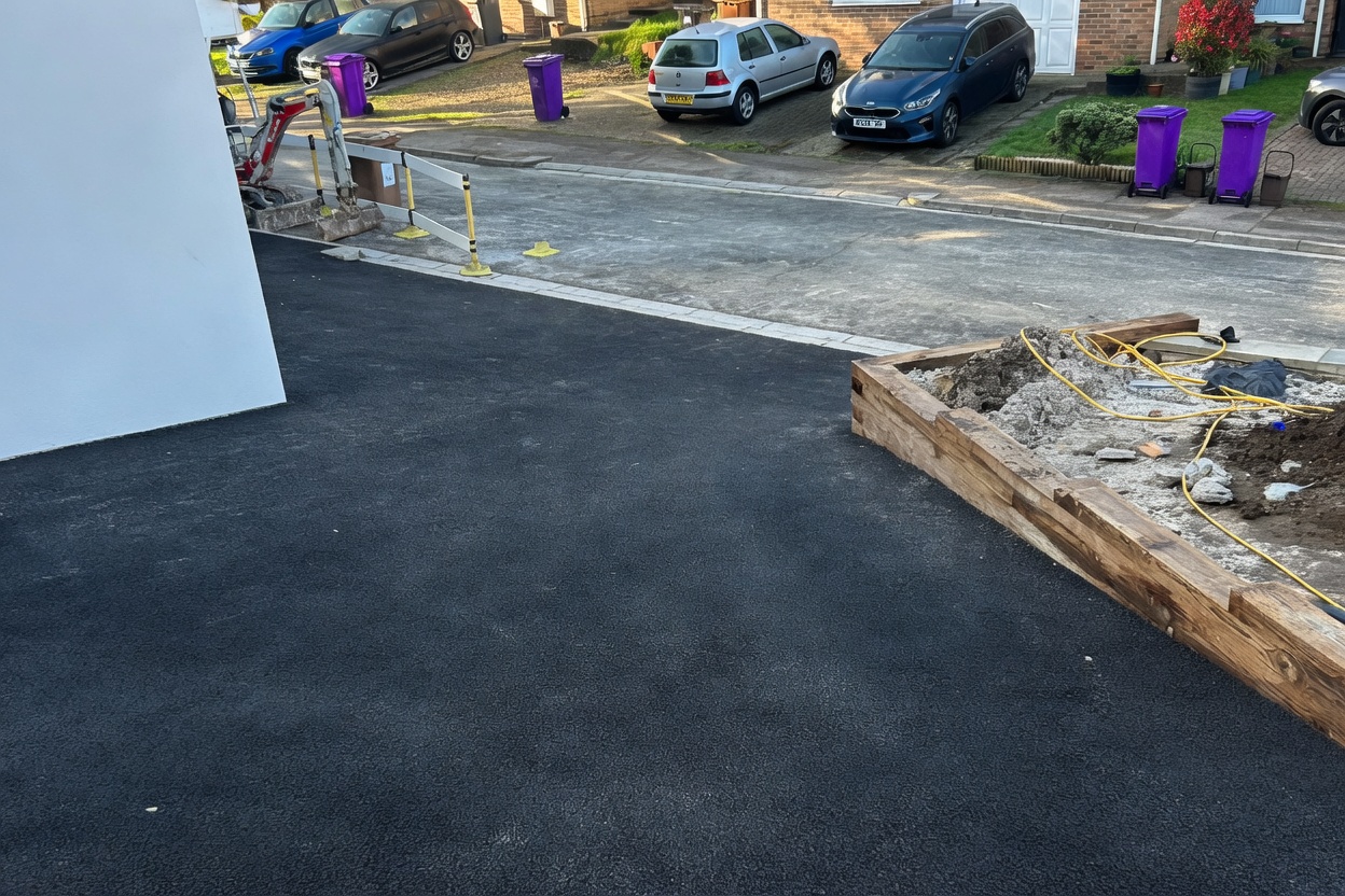 Tarmac being laid with mini-excavator and edging formers on site