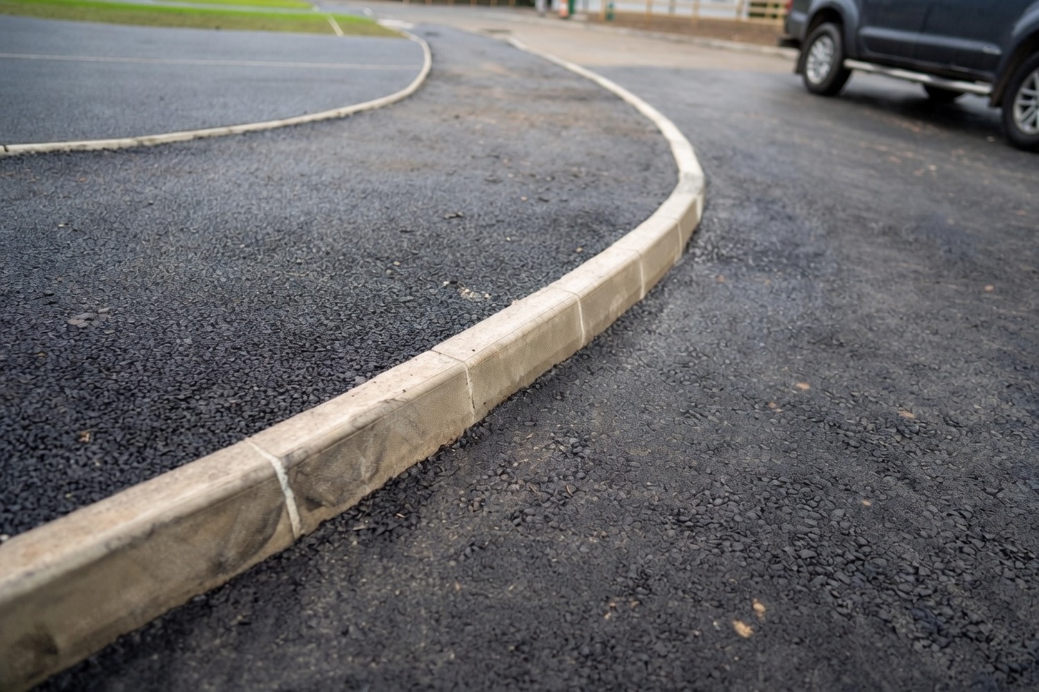 Curved asphalt path with crisp kerb-edged finish past a lawn