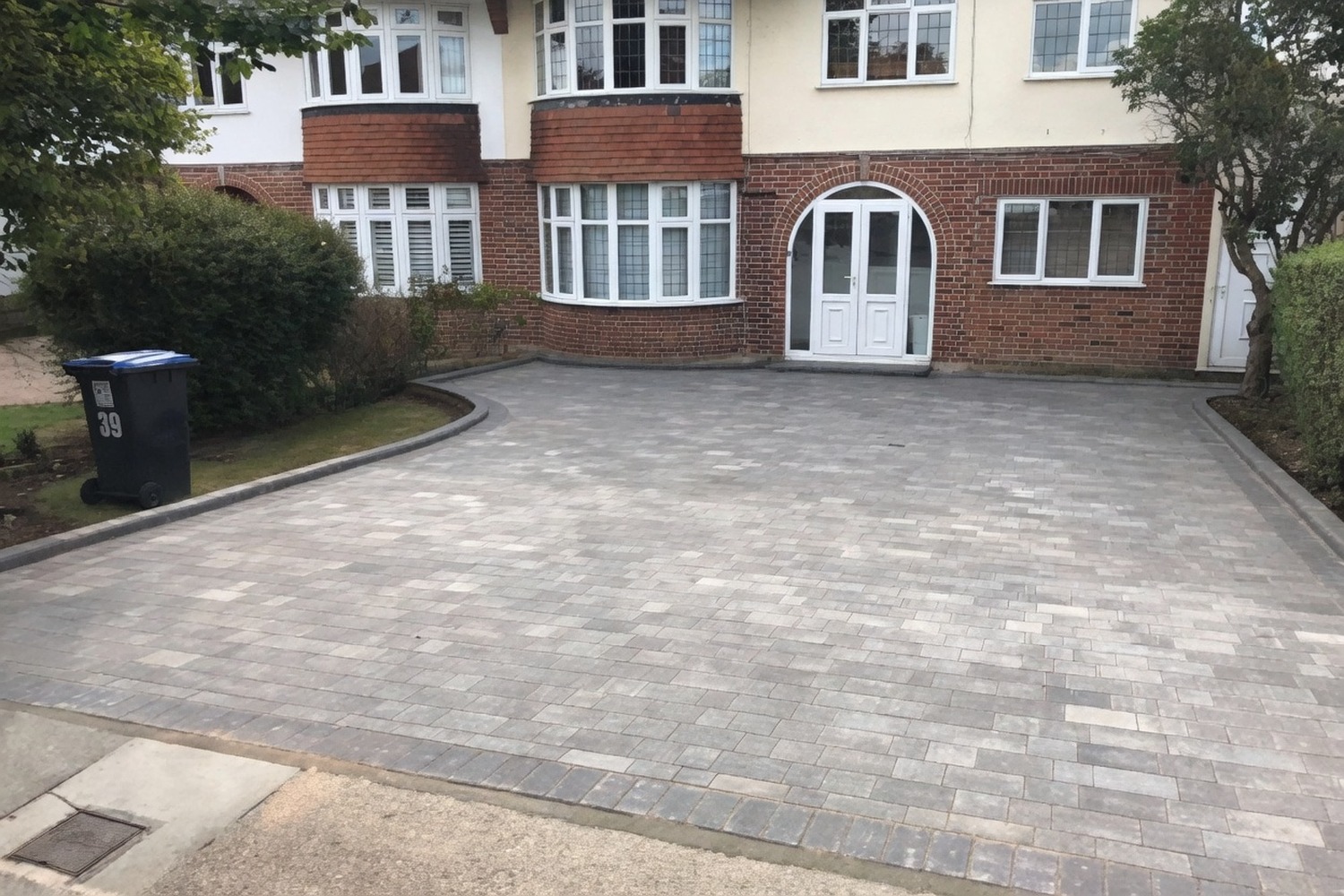 Block-paved driveway in front of a brick house