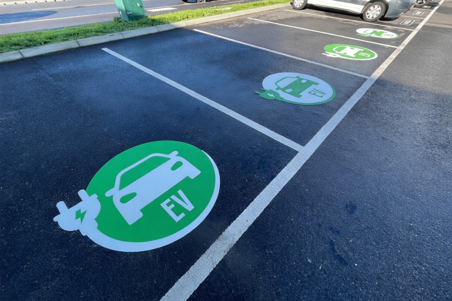 Green EV charging bay symbols painted on a row of car-park bays